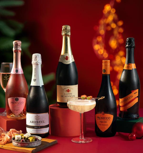 A festive selection of sparkling wines, champagne, and prosecco bottles with a filled glass.