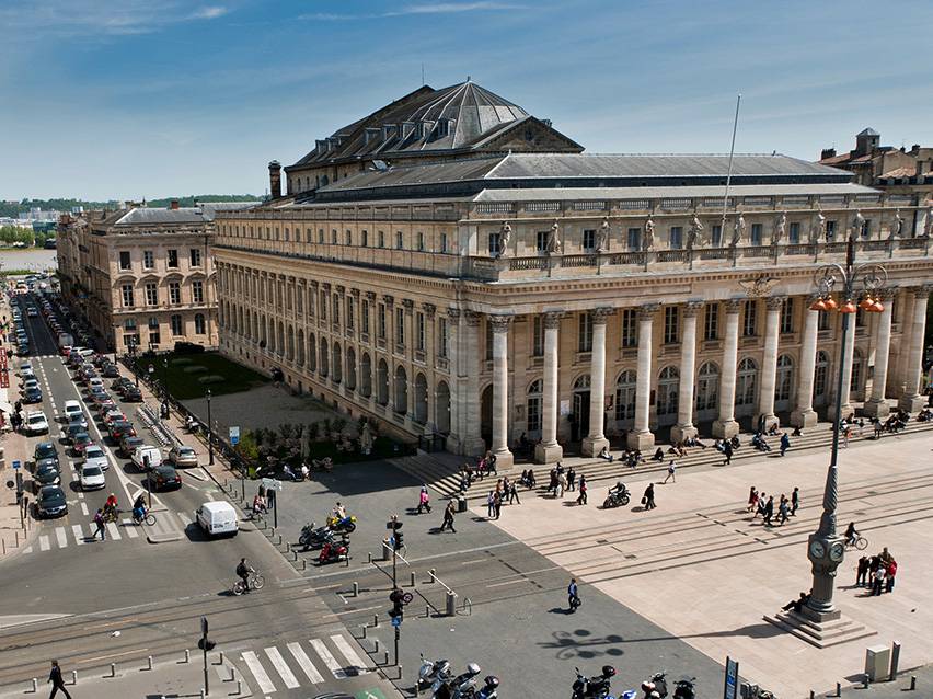 Aerial view of the Grand Théâtre de Bordeaux with people and cars on the street.