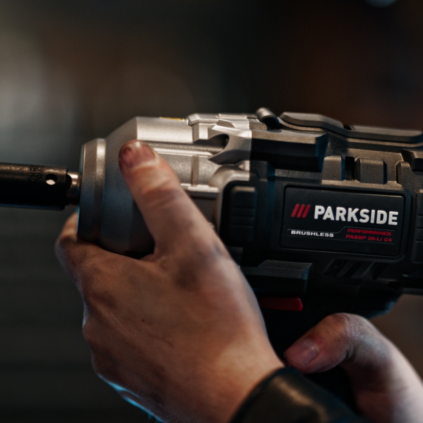 A person holds a Parkside Performance impact drill, with dirty hands.