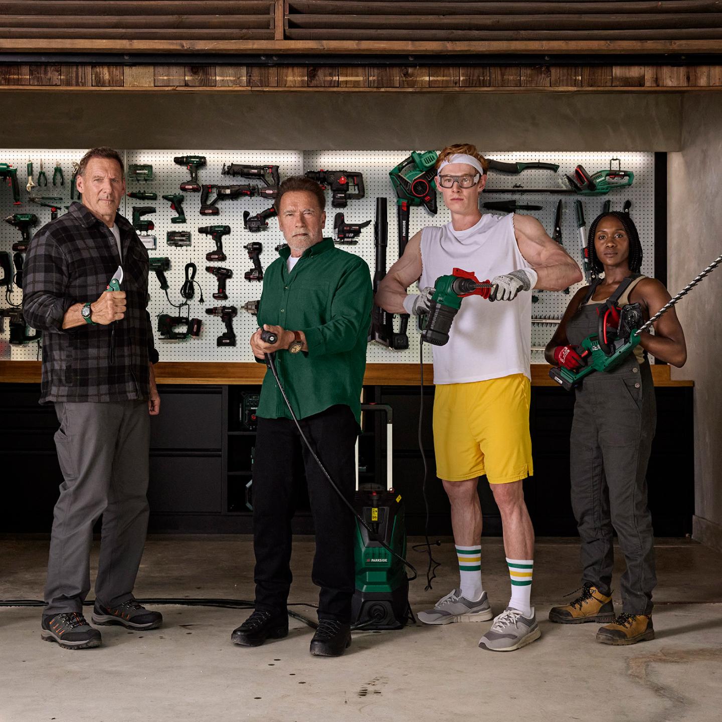 Four people, including Arnold Schwarzenegger, pose with Parkside tools in a workshop.