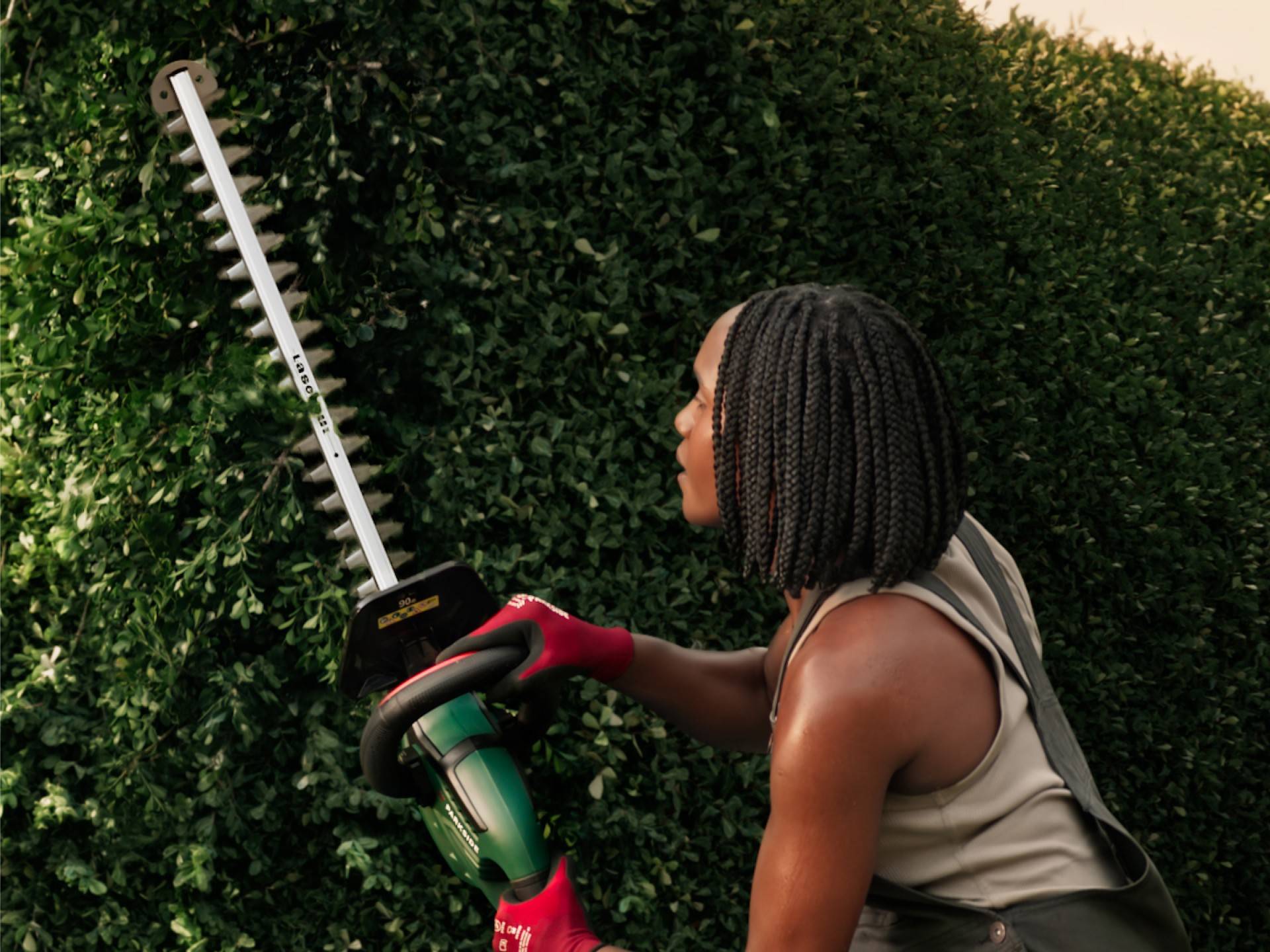 Person trimming a hedge with a Parkside hedge trimmer.