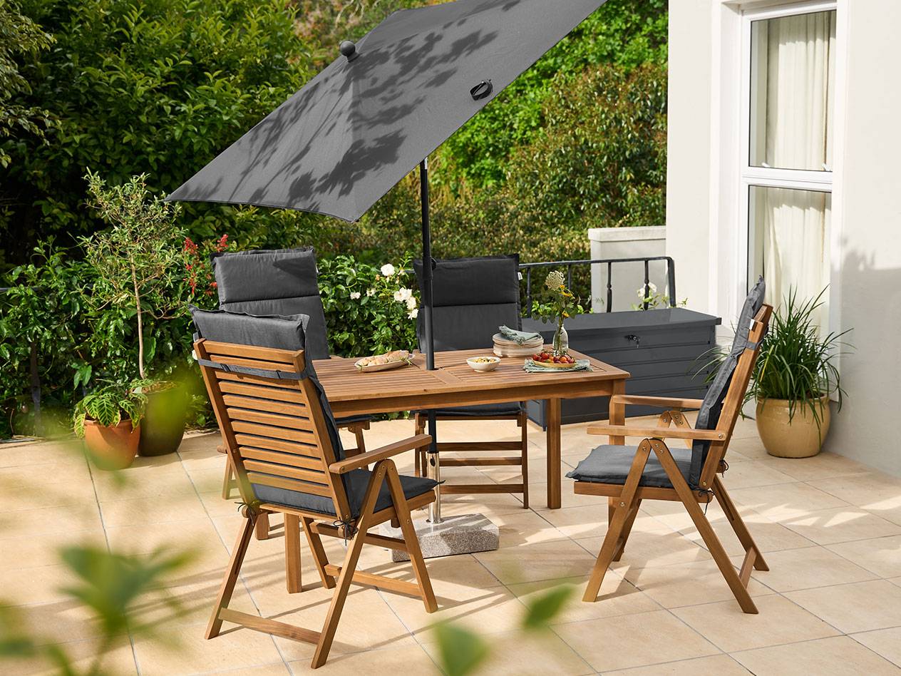Wooden garden dining set with grey cushions and a large grey parasol on a patio.