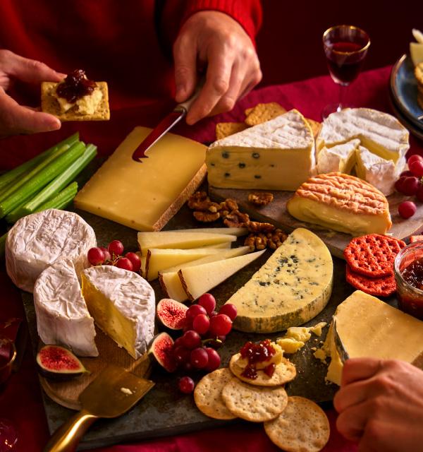 A festive cheese board selection with crackers, grapes, figs, and celery.