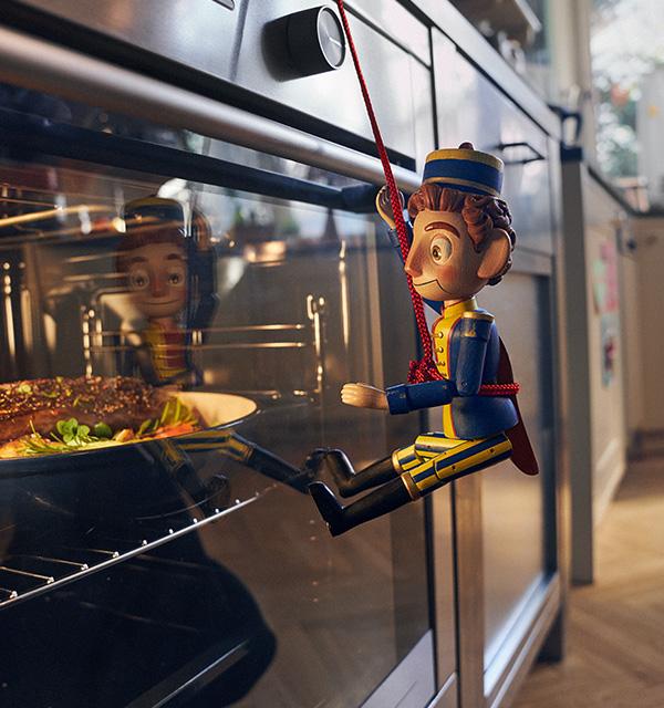 A toy soldier figurine rappelling down an oven door with food cooking inside.