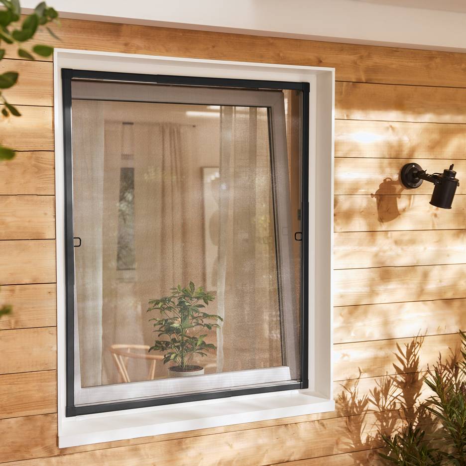 Window with a retractable insect screen on a wooden facade, with a plant inside.
