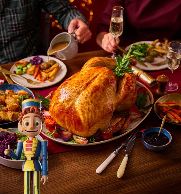 A festive Christmas dinner table featuring a large roasted turkey, side dishes, and a toy soldier.