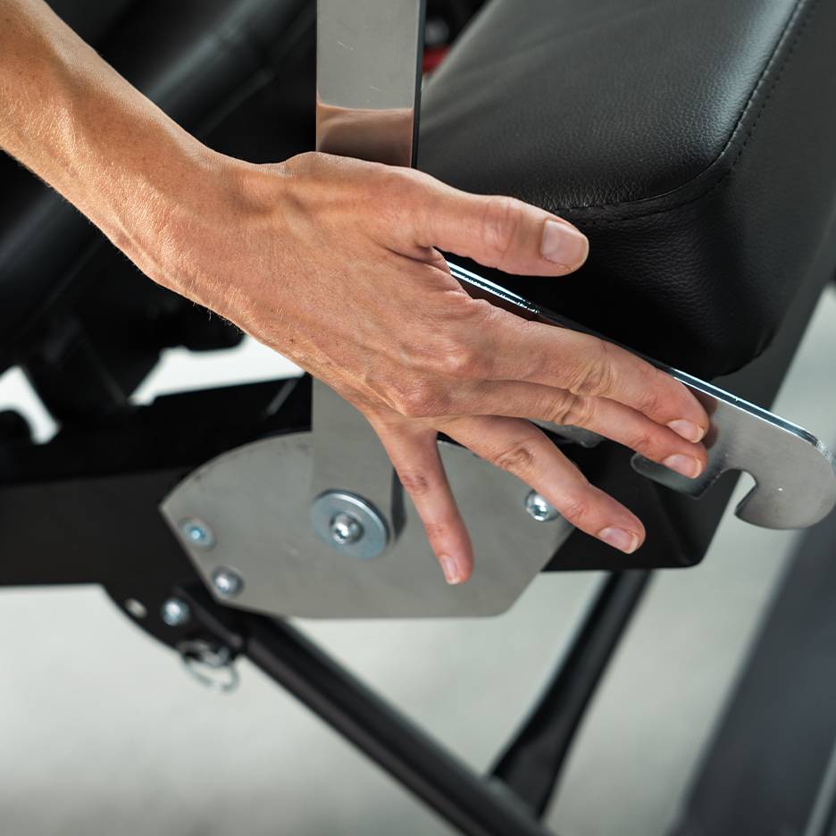 Hand adjusting a lever on a black exercise bench.