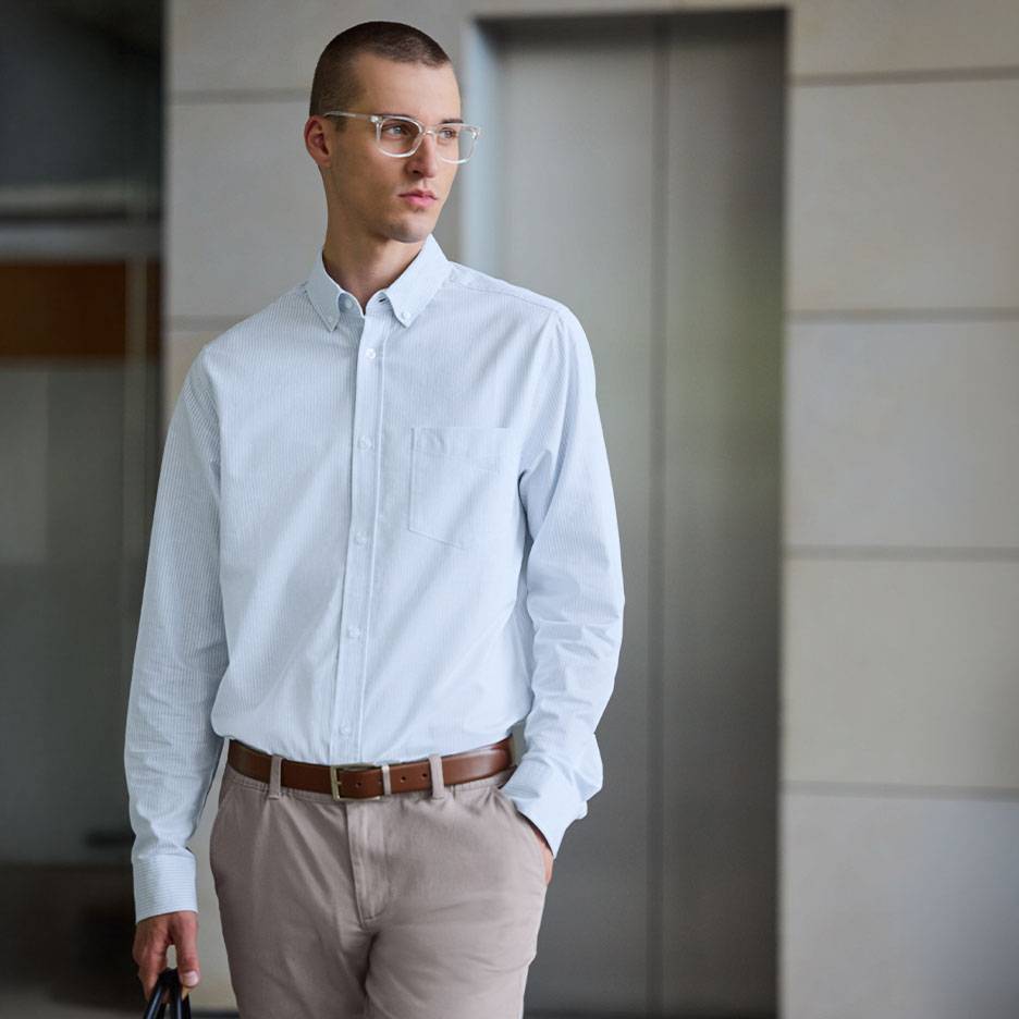 Man in a light blue striped shirt and beige trousers with a brown belt.