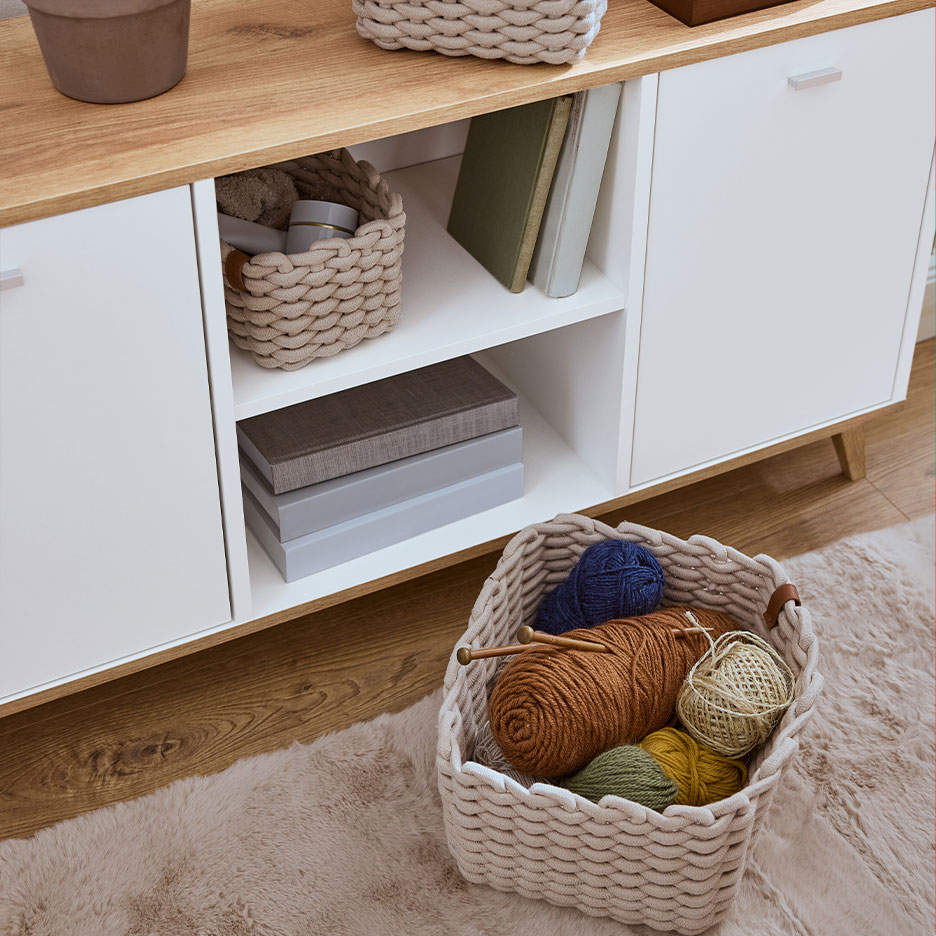 Wooden storage cabinet with braided baskets and knitting yarns.