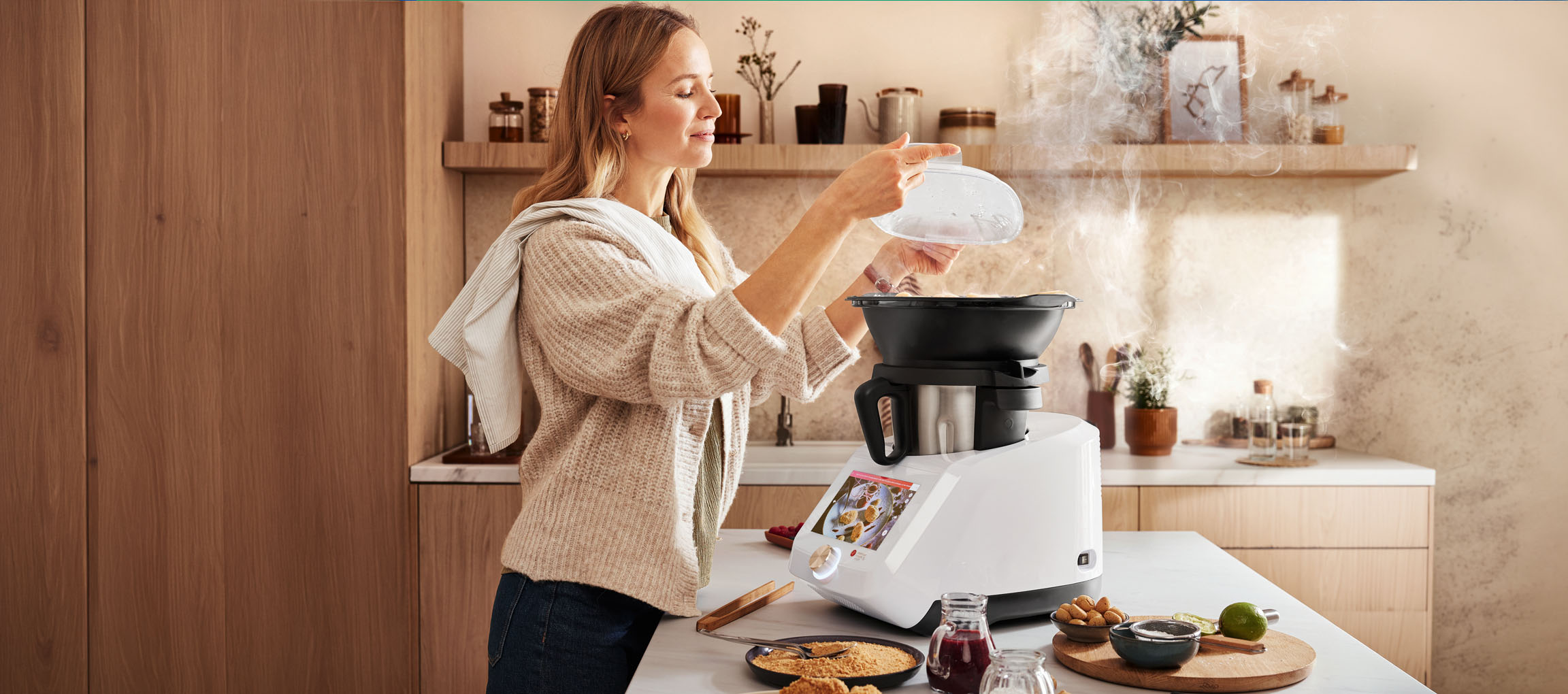 Woman cooking with a kitchen machine, steam rising, in a modern kitchen.
