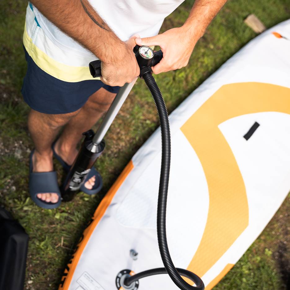 Man inflating an inflatable paddleboard with a hand pump.