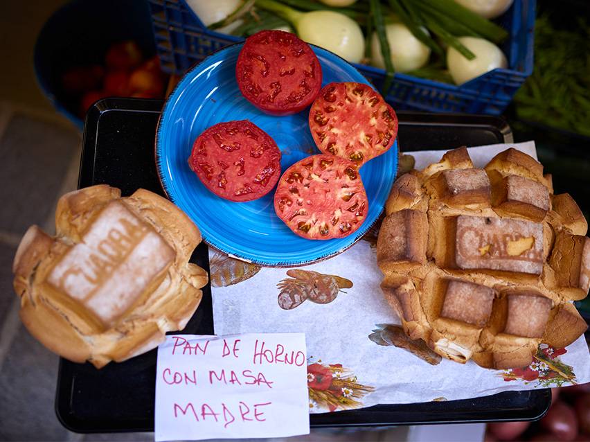 Fresh tomatoes and homemade sourdough bread at a market.