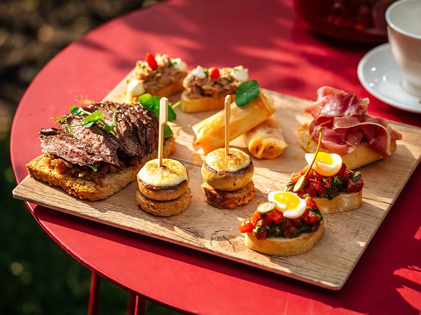 Assortment of tapas and canapés, including steak, mushrooms, spring rolls, and bruschetta.
