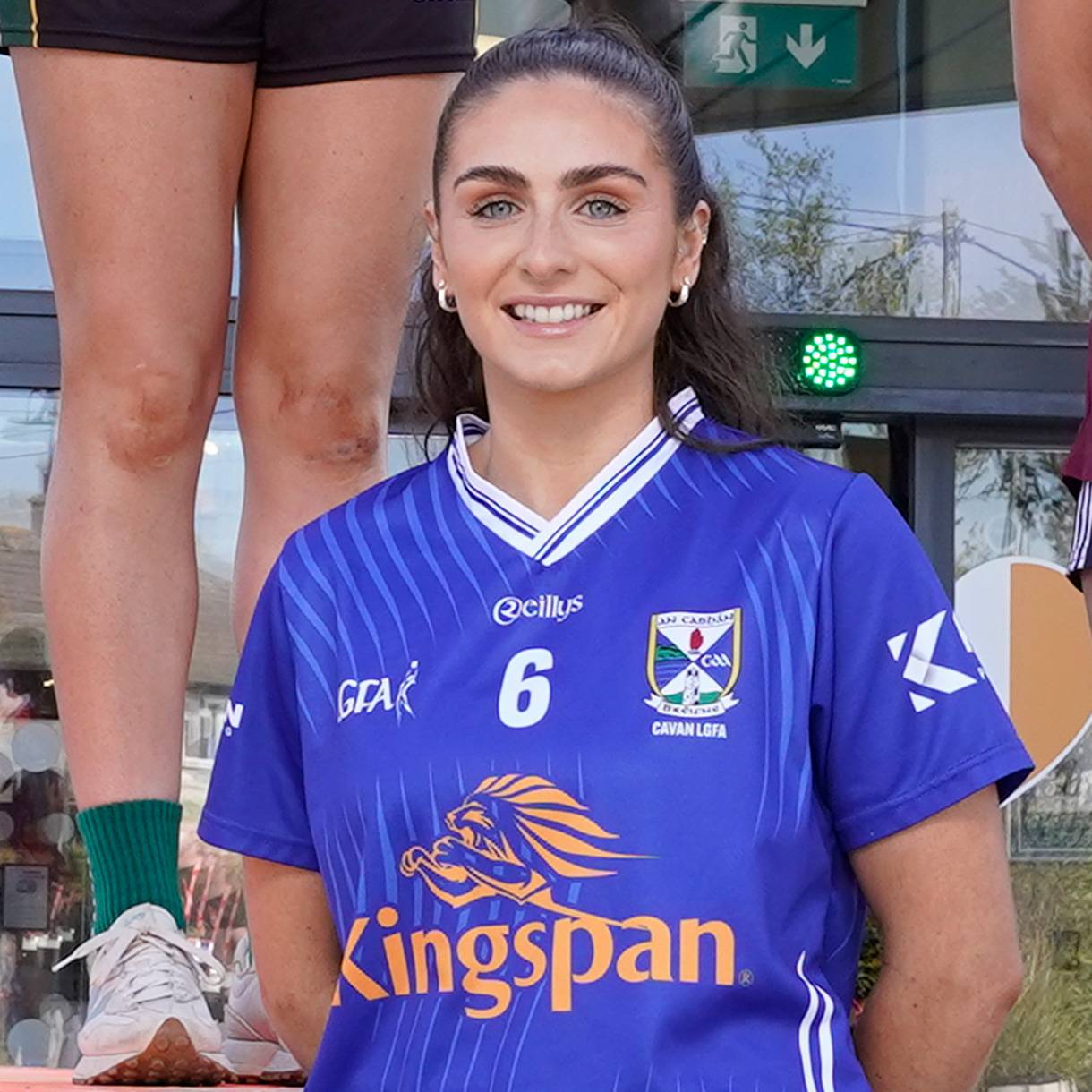 Woman in a blue sports jersey with number 6, smiling at the camera.