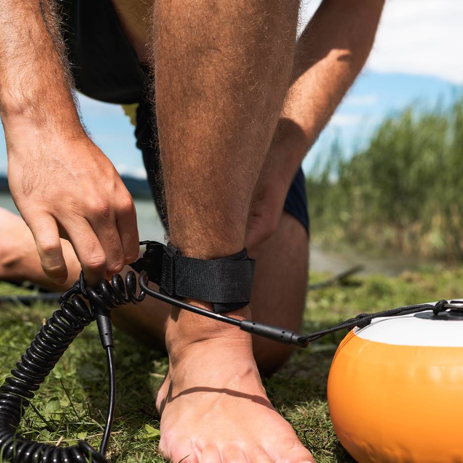 Man attaching a paddleboard leash to his ankle.