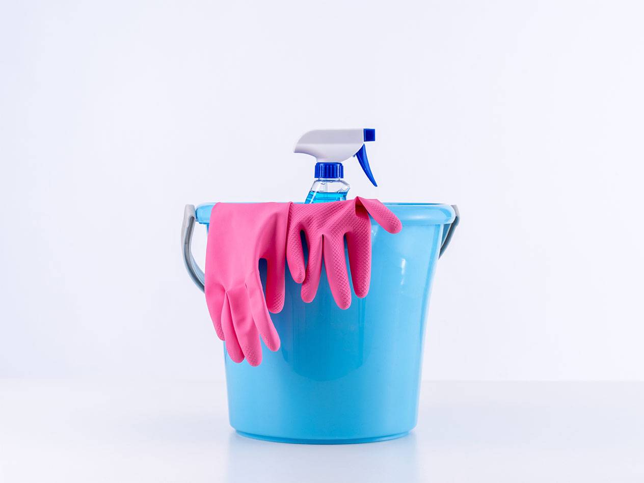 Blue bucket with pink cleaning gloves and a spray bottle.
