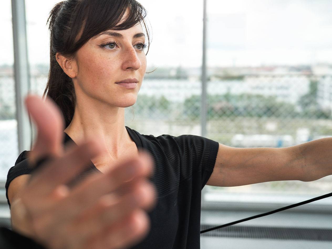 Woman exercising with a resistance band in front of a window.