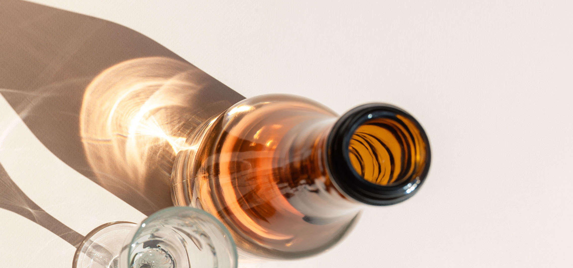 Glasses and bottle with shadows and light reflections on a light background