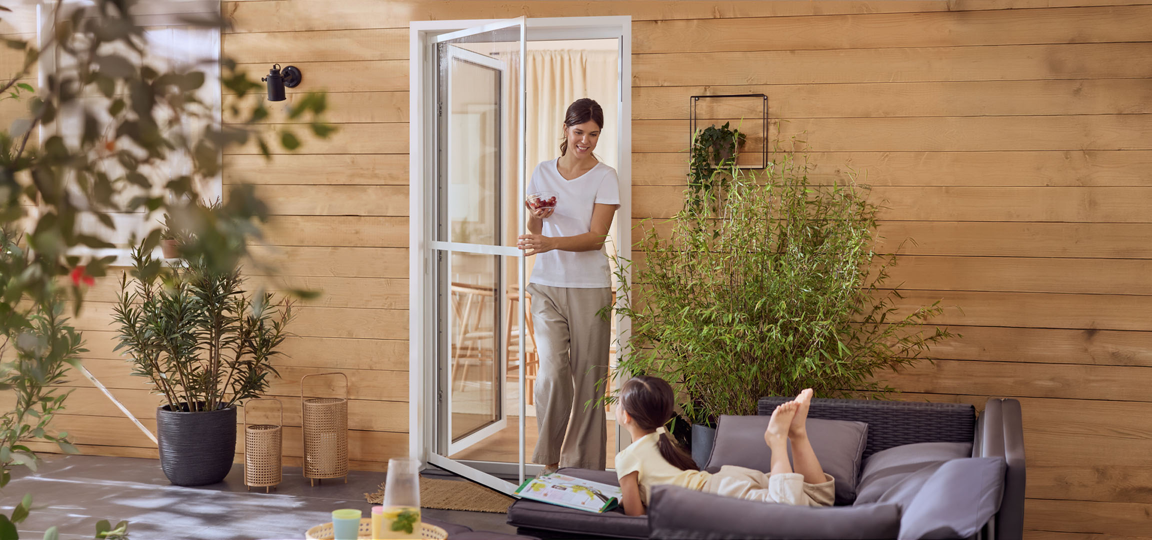 Woman and girl enjoying a patio with outdoor furniture and plants.