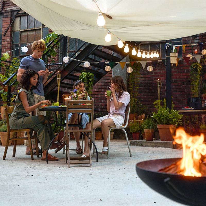 Friends enjoying an outdoor dinner under string lights.
