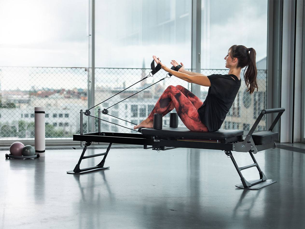 Woman doing Pilates on a reformer with a city view.