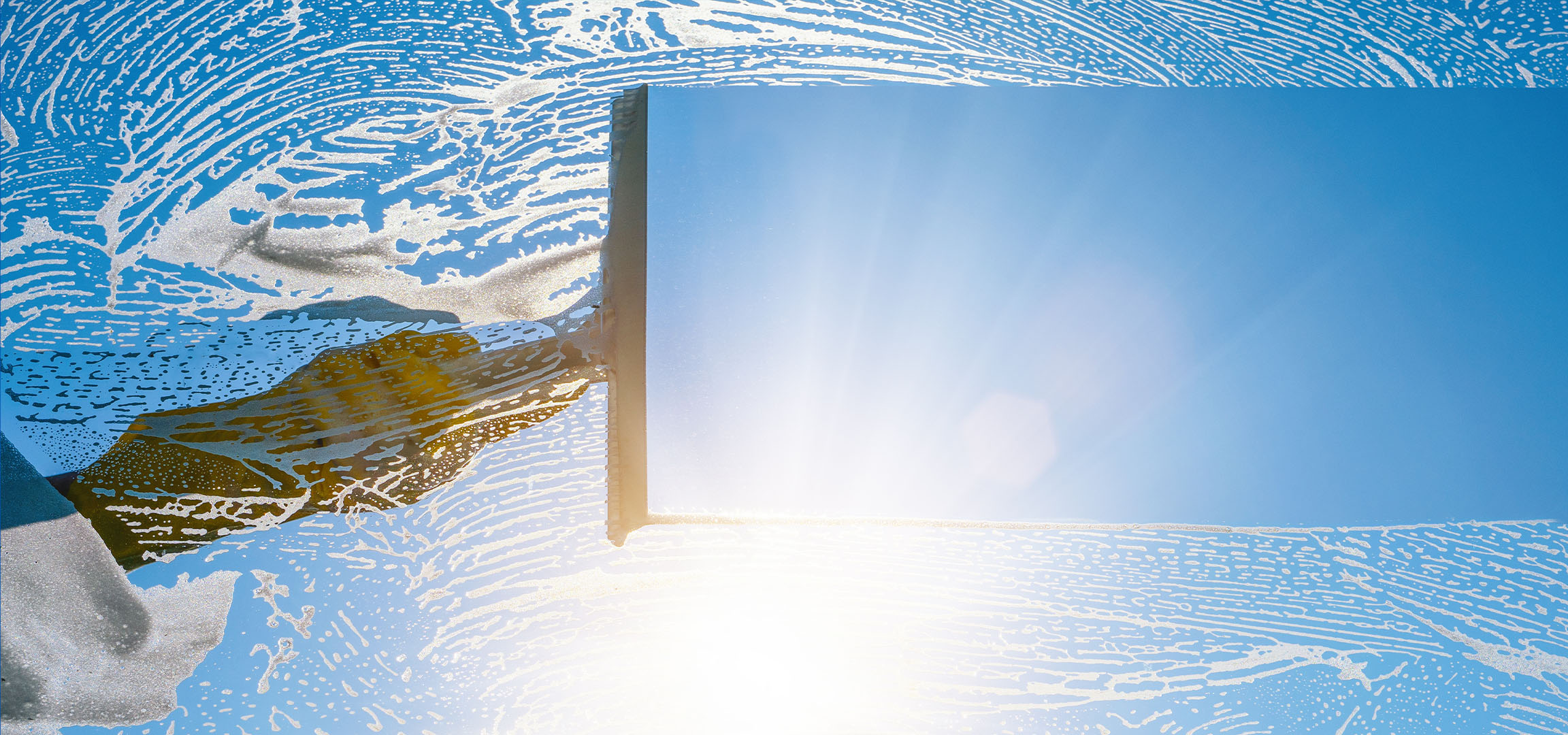 Window cleaning with soap suds on a blue sky.