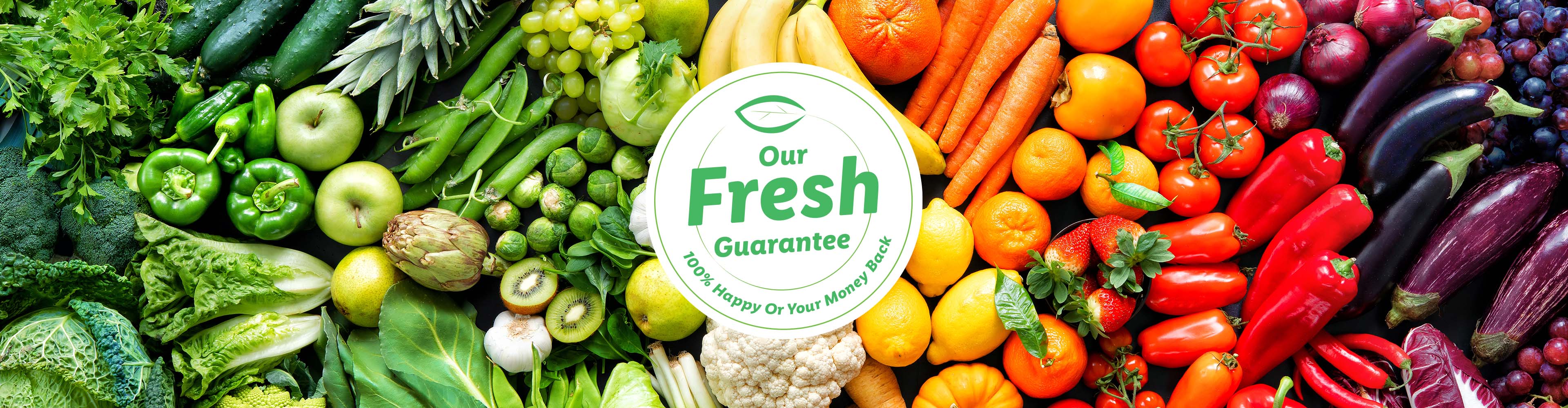 A vibrant display of fresh produce, including green vegetables, fruits, and red vegetables, with a 'Our Fresh Guarantee' logo.