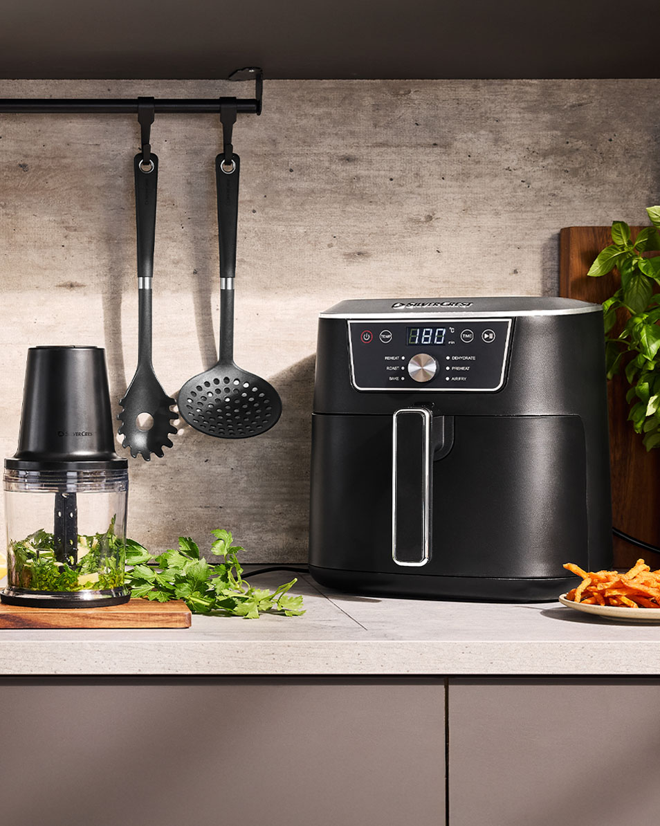 SilverCrest air fryer and food chopper on a kitchen counter with fresh herbs.