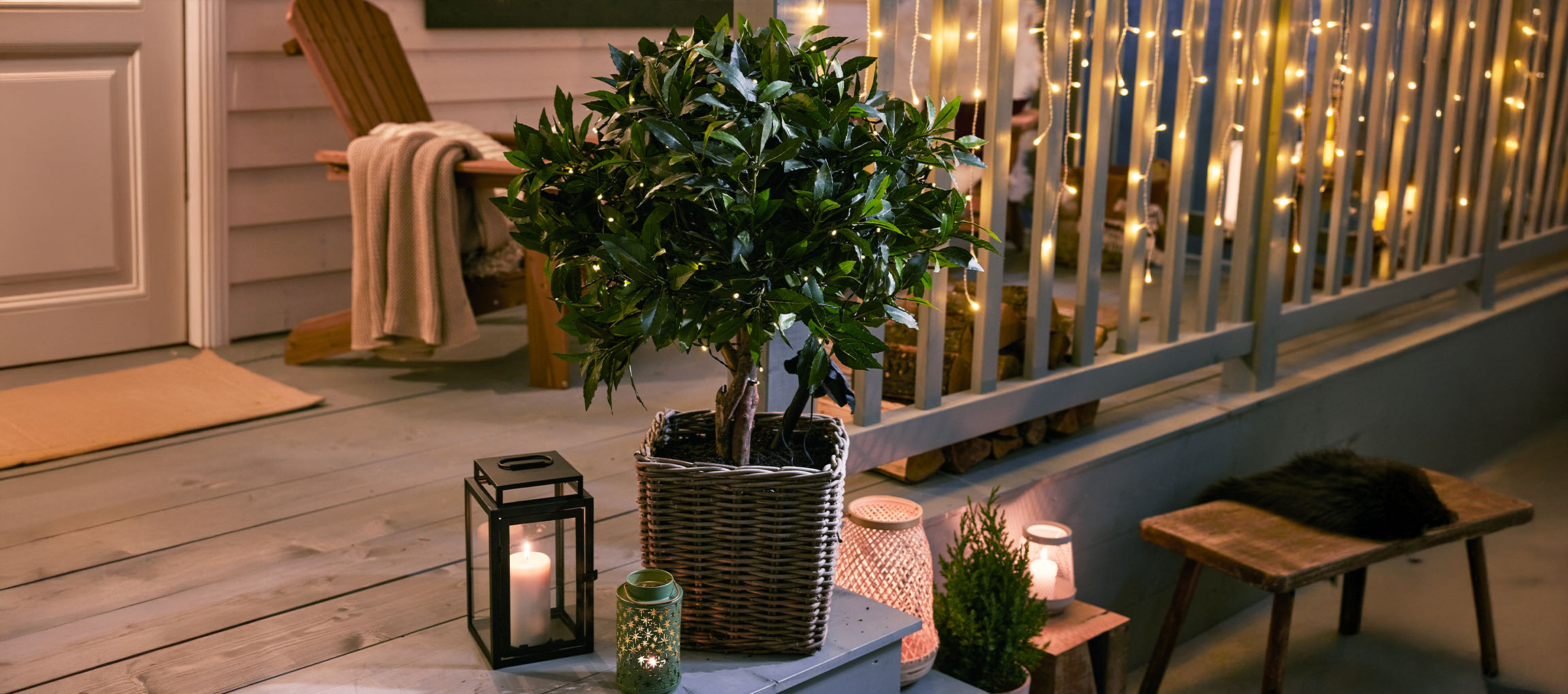 Cozy porch with a potted plant, lanterns, and string lights for a warm ambiance.