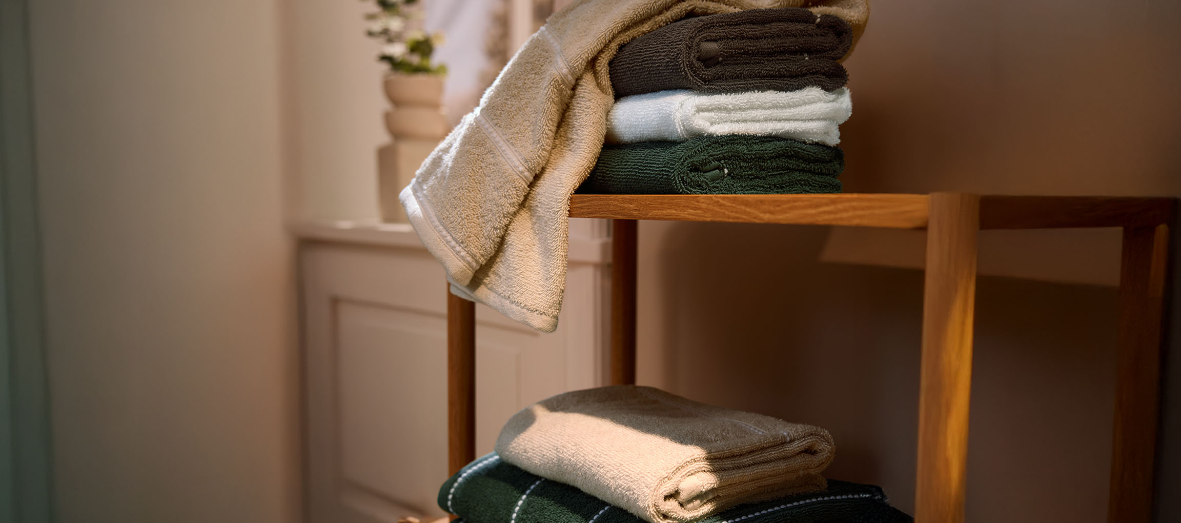 Assorted colored bath towels stacked on a wooden shelf.