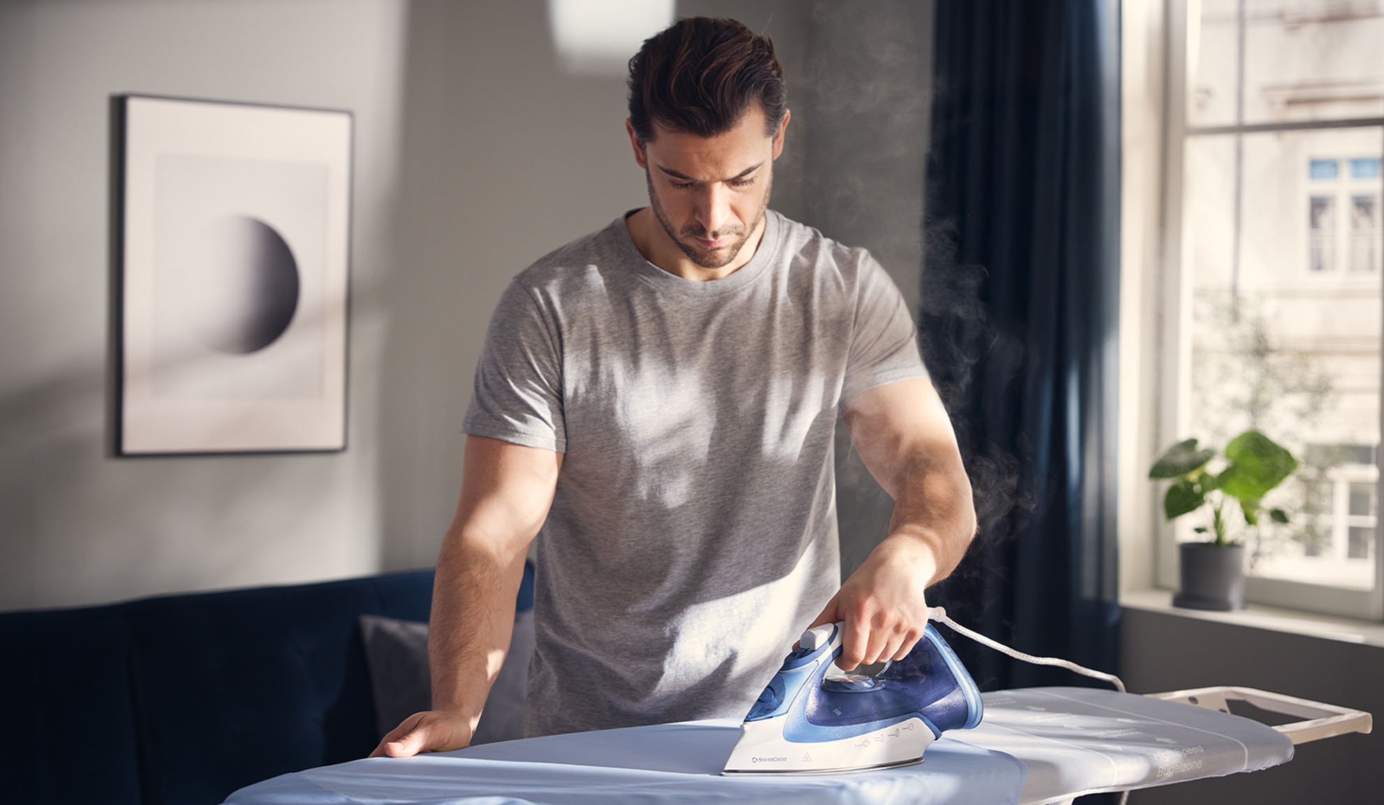 Man ironing clothes with a steam iron on an ironing board