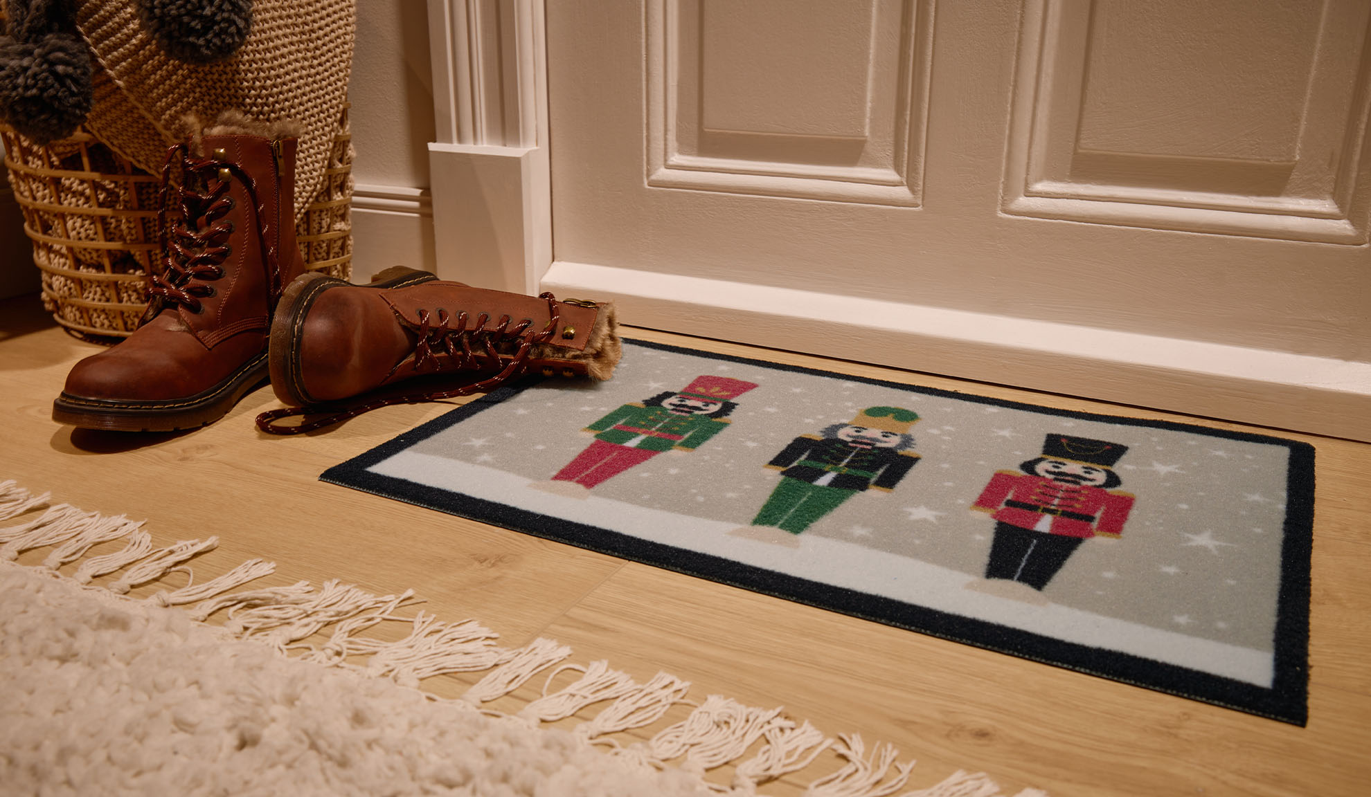 Christmas doormat with nutcracker soldiers, brown boots, and wicker basket at the entrance.