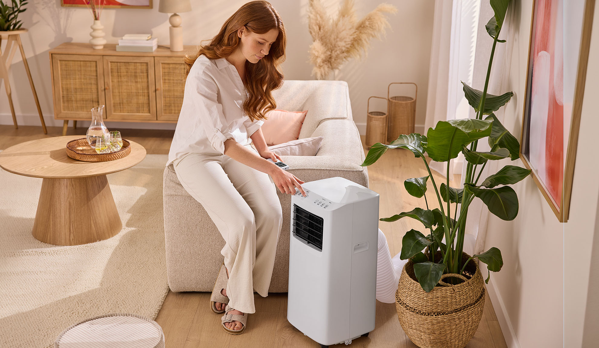 Woman adjusting a portable air conditioner in a cozy living room.