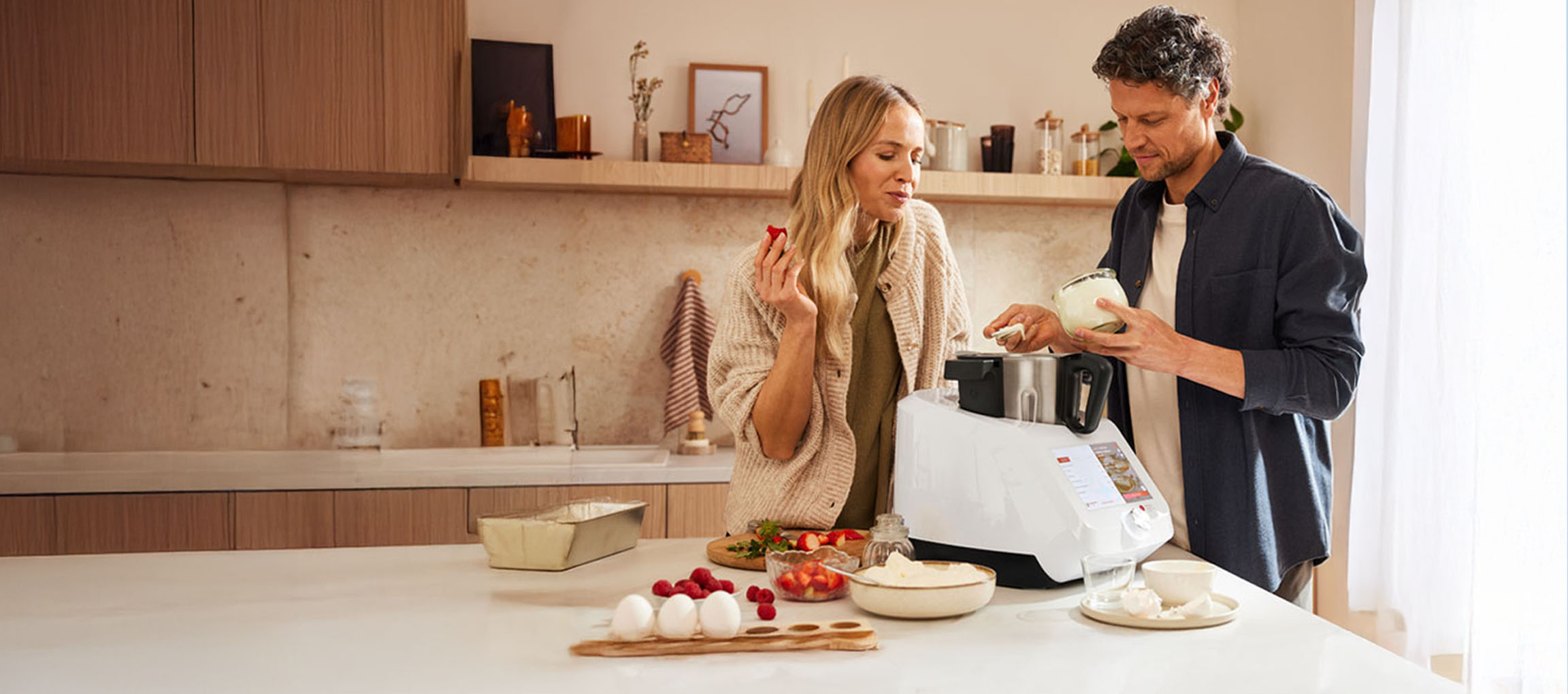 A couple cooking together with a modern kitchen machine in a bright kitchen.