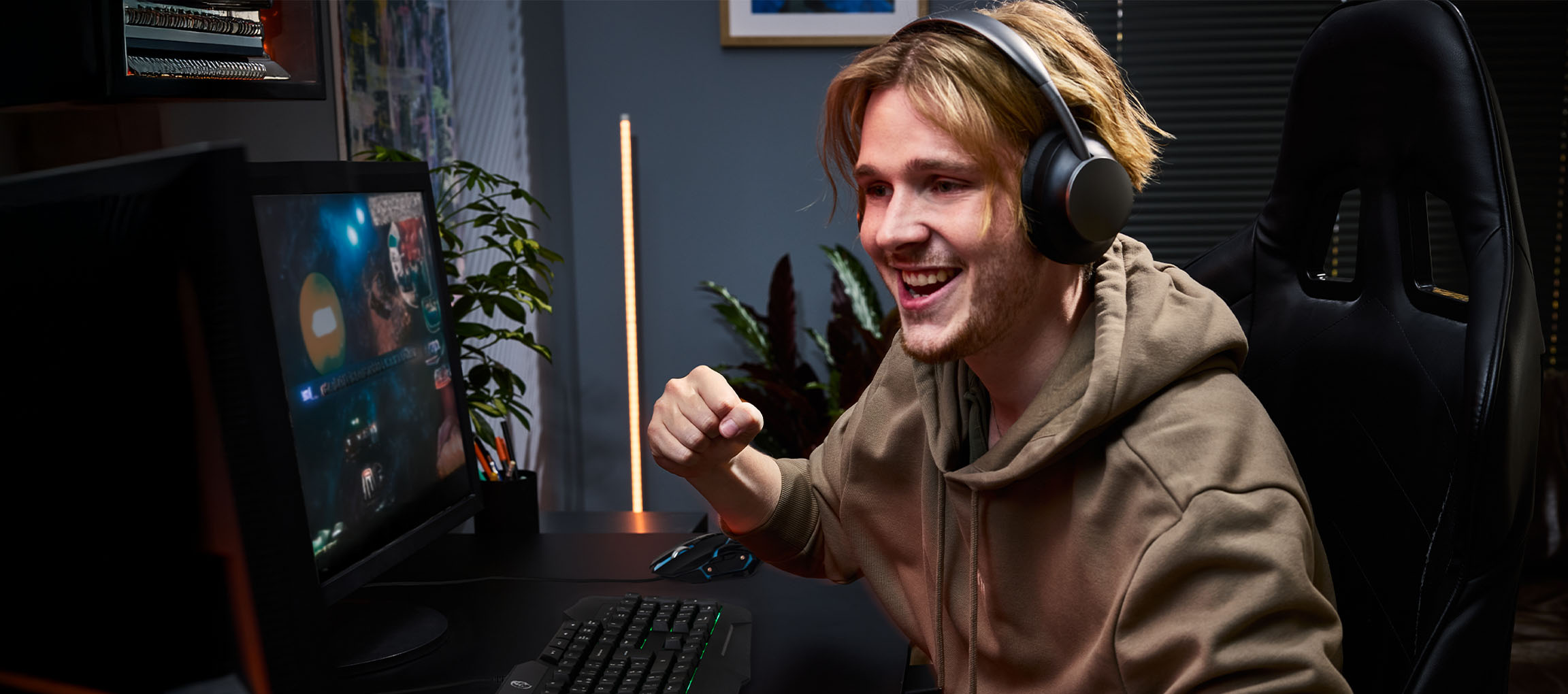 Young man with headphones playing video games with a gaming keyboard and mouse