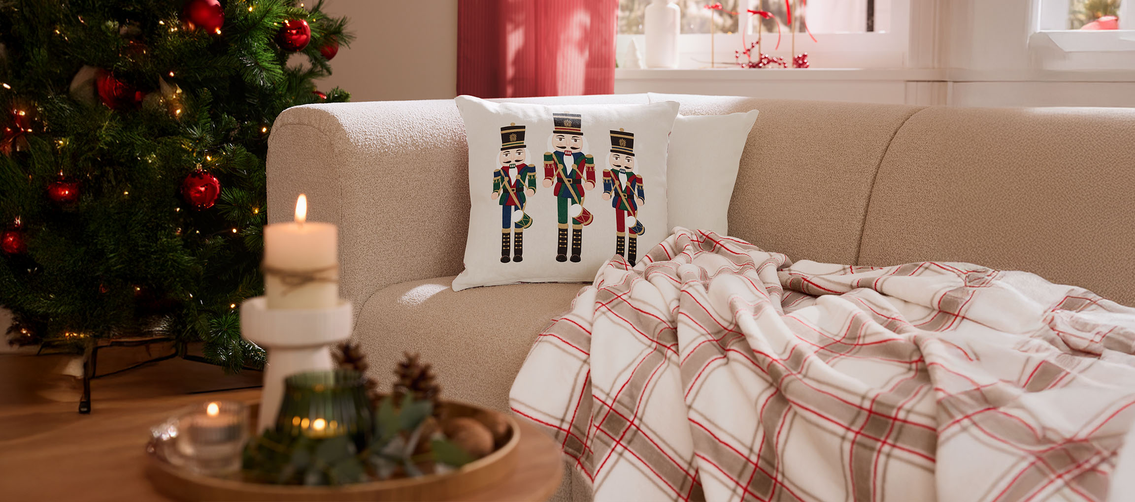 Christmas living room with nutcracker pillow, plaid throw, and candles.