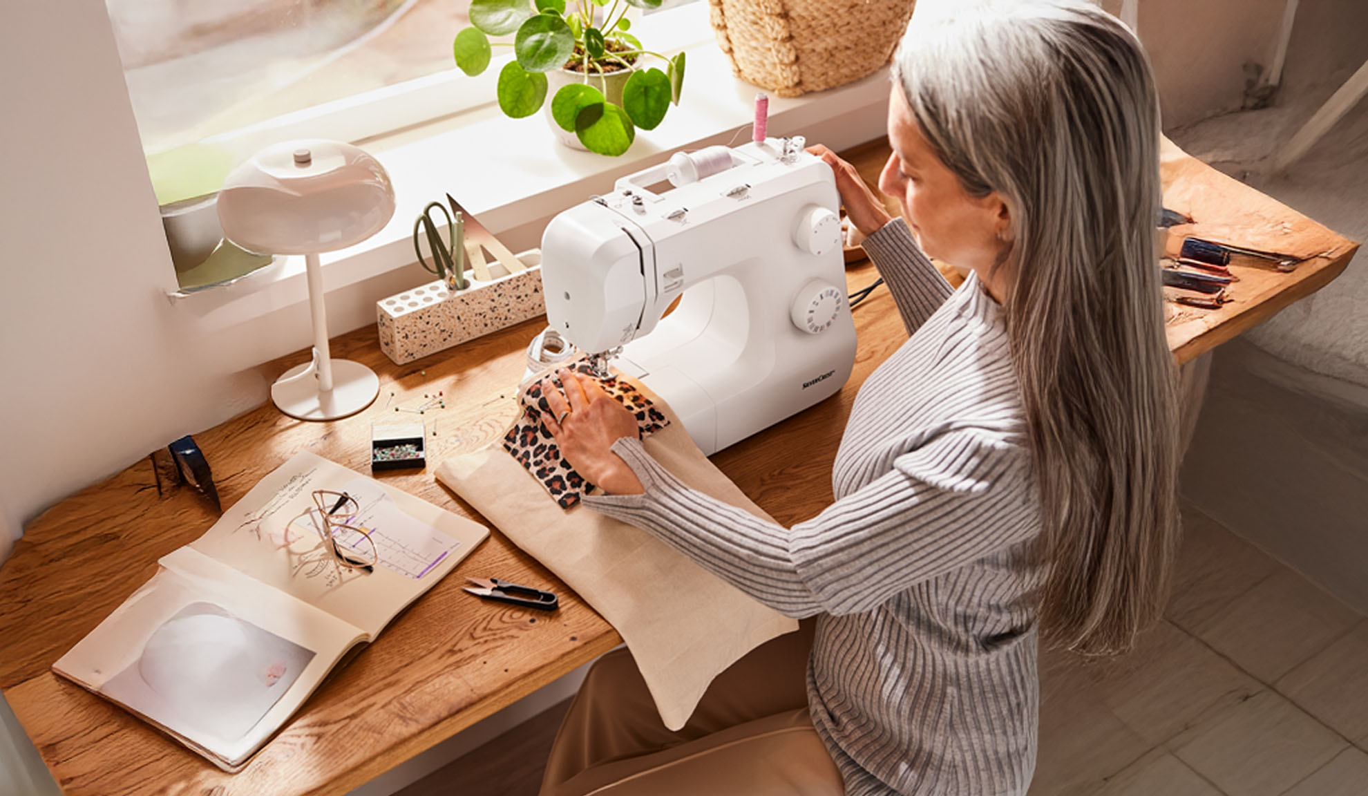A woman sews leopard print fabric on a SilverCrest sewing machine in a home setting.