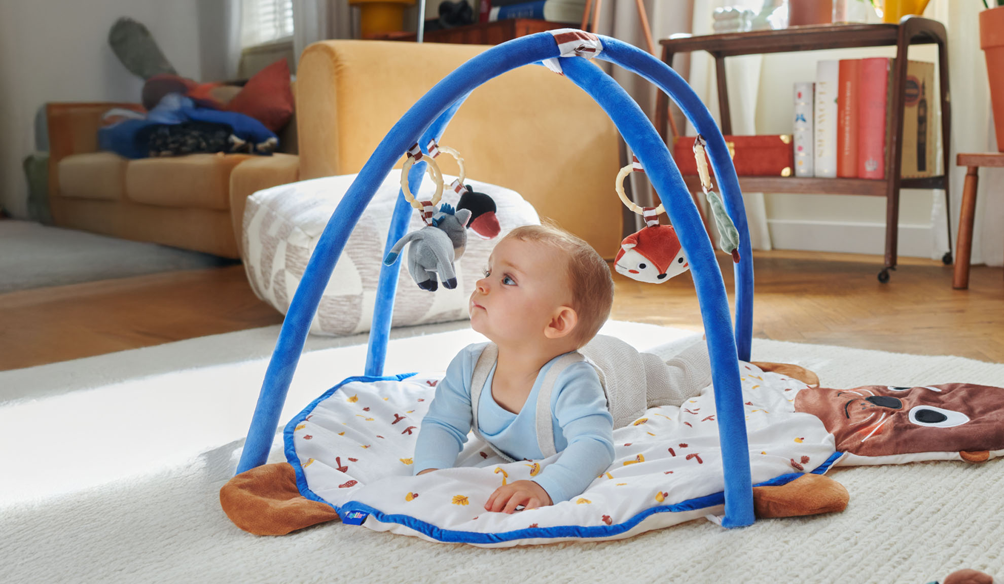 A baby plays on a Tiny Love playmat with an animal-shaped arch.