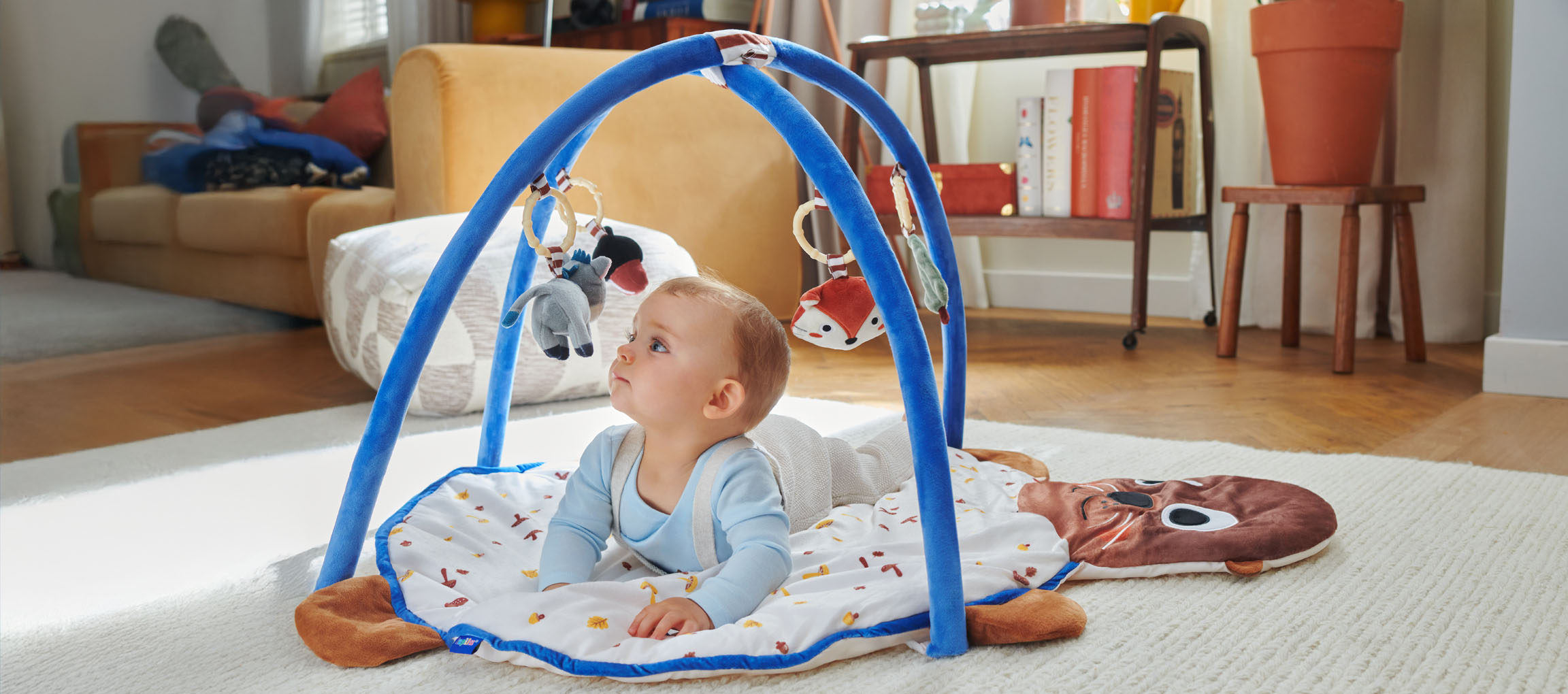 A baby plays with a Little Dutch playmat shaped like a seal.