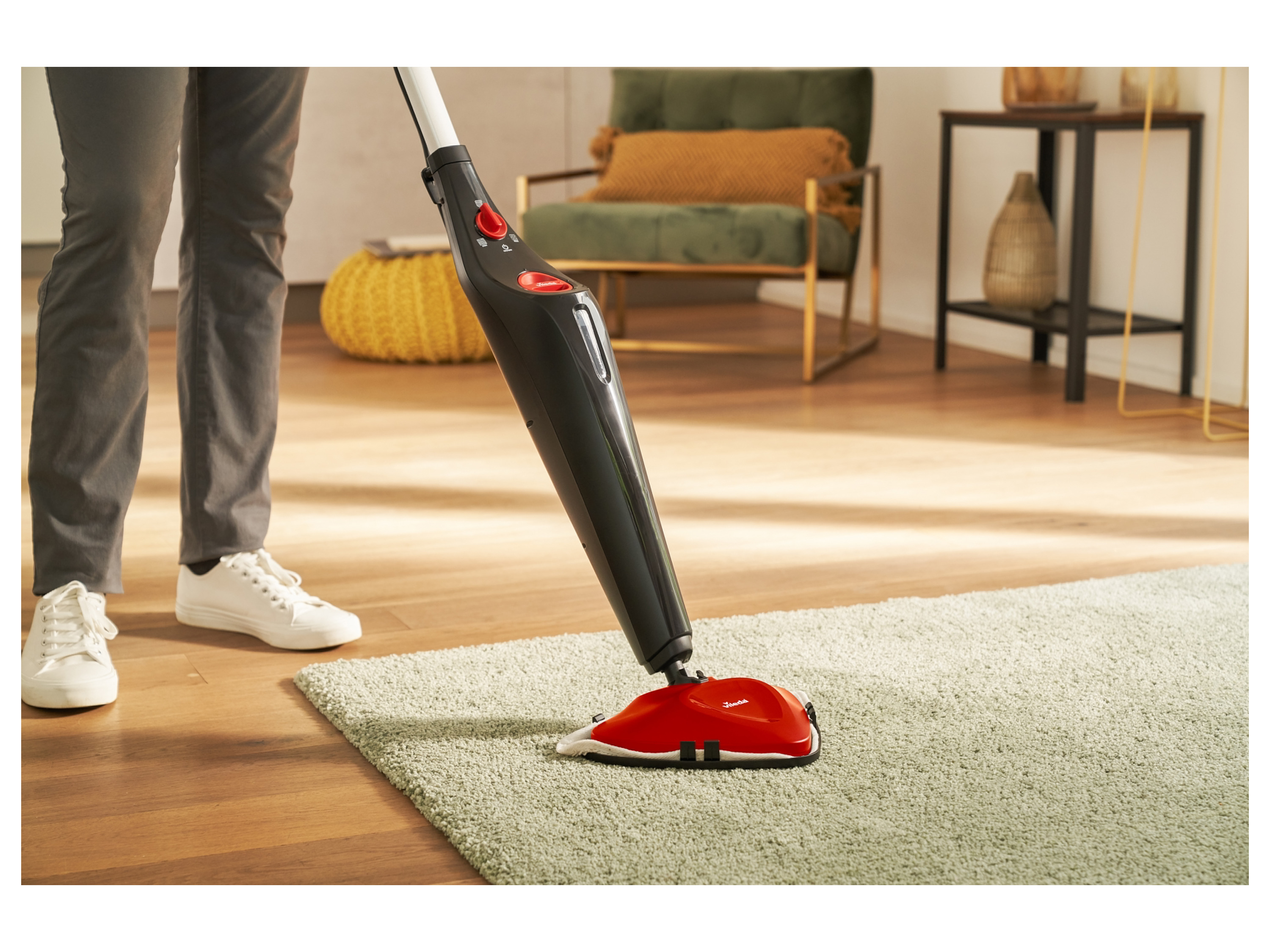 A person cleaning a light green rug with a Vileda steam mop.