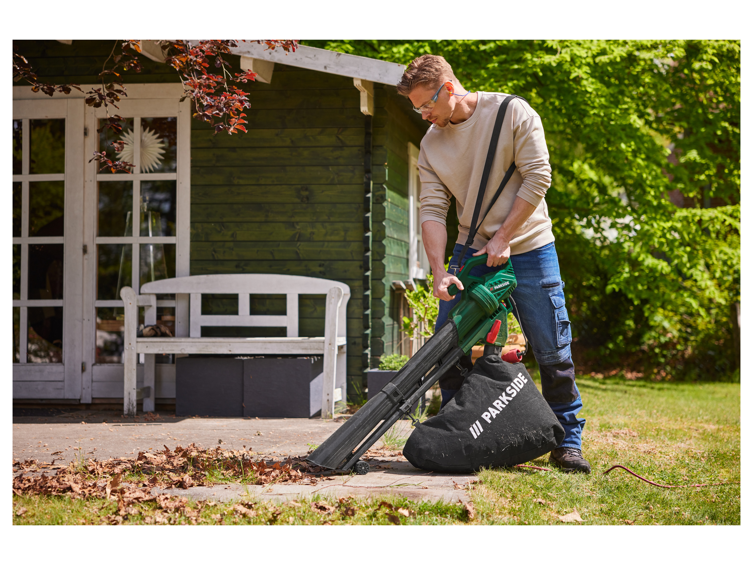 Man using a Parkside leaf blower to clear leaves from a patio.