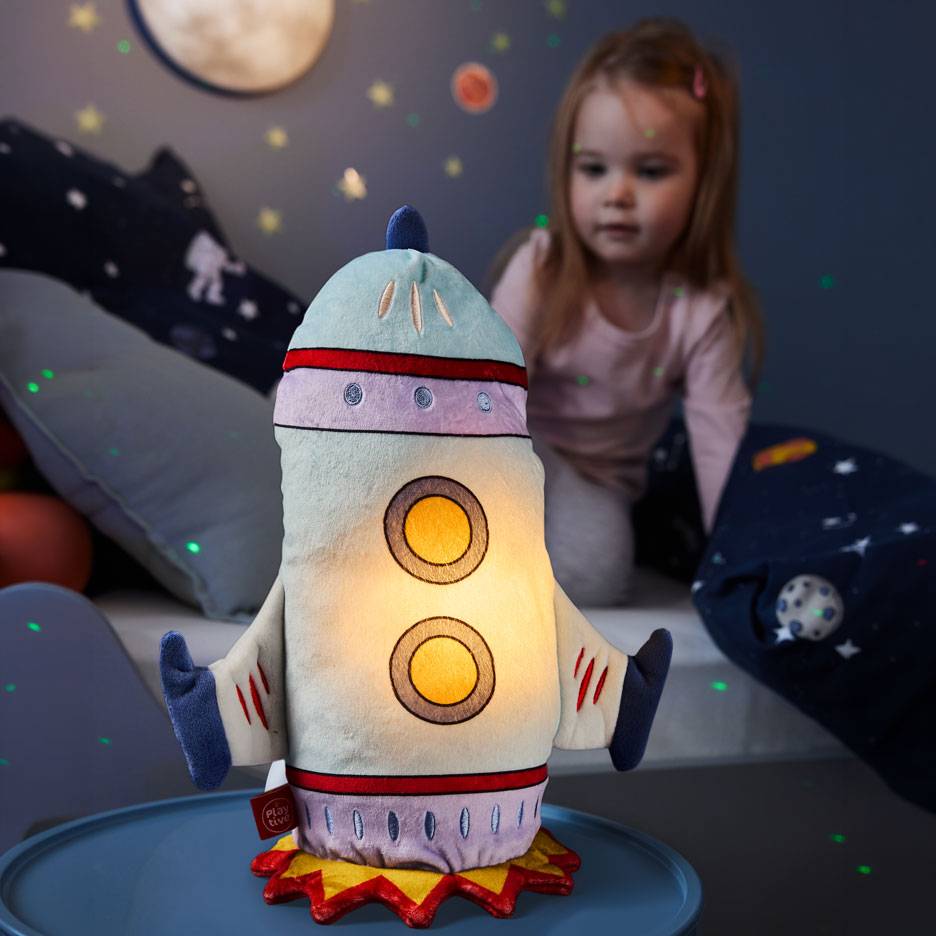 Girl looks at a rocket-shaped night light in a space-themed room.