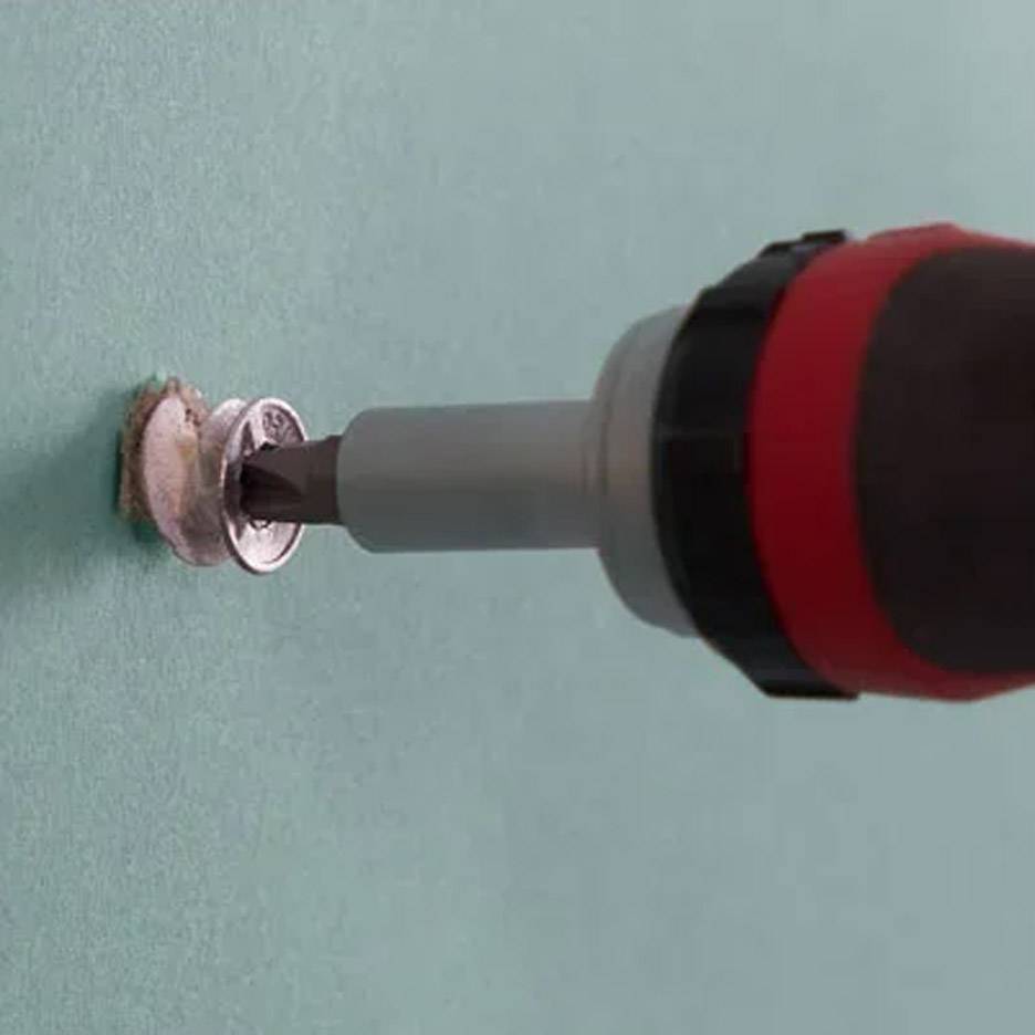 Electric screwdriver with a drill bit inserting a screw into the wall.